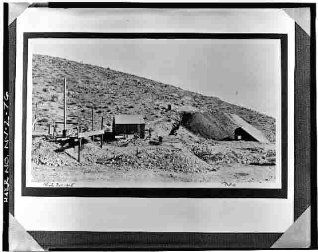 A black and white photograph of a small mining operation on a hillside.