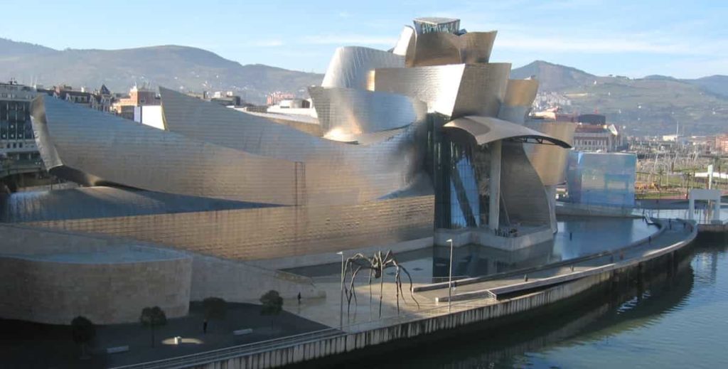 A photo of the Guggenheim Museum in Bilbao, which sits shoreside on a dock.