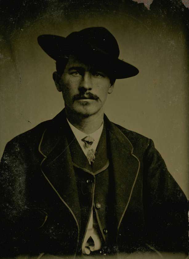 Black and white photograph of Wyatt Earp in business suit with hat tilted.