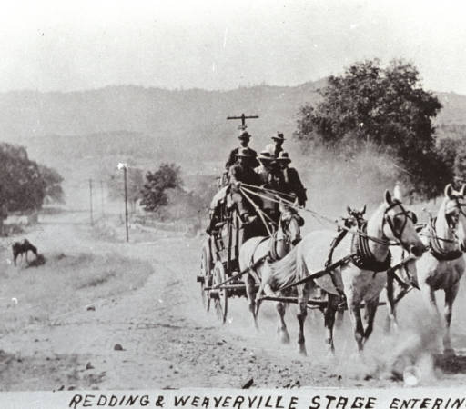 Two men on a horse-drawn carriage in the country with the words “Redding & Weaverville Stage Entering Shasta, Cal.”